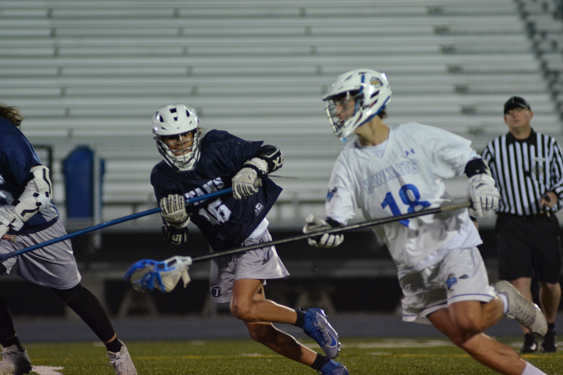 High school lacrosse players running under stadium lights