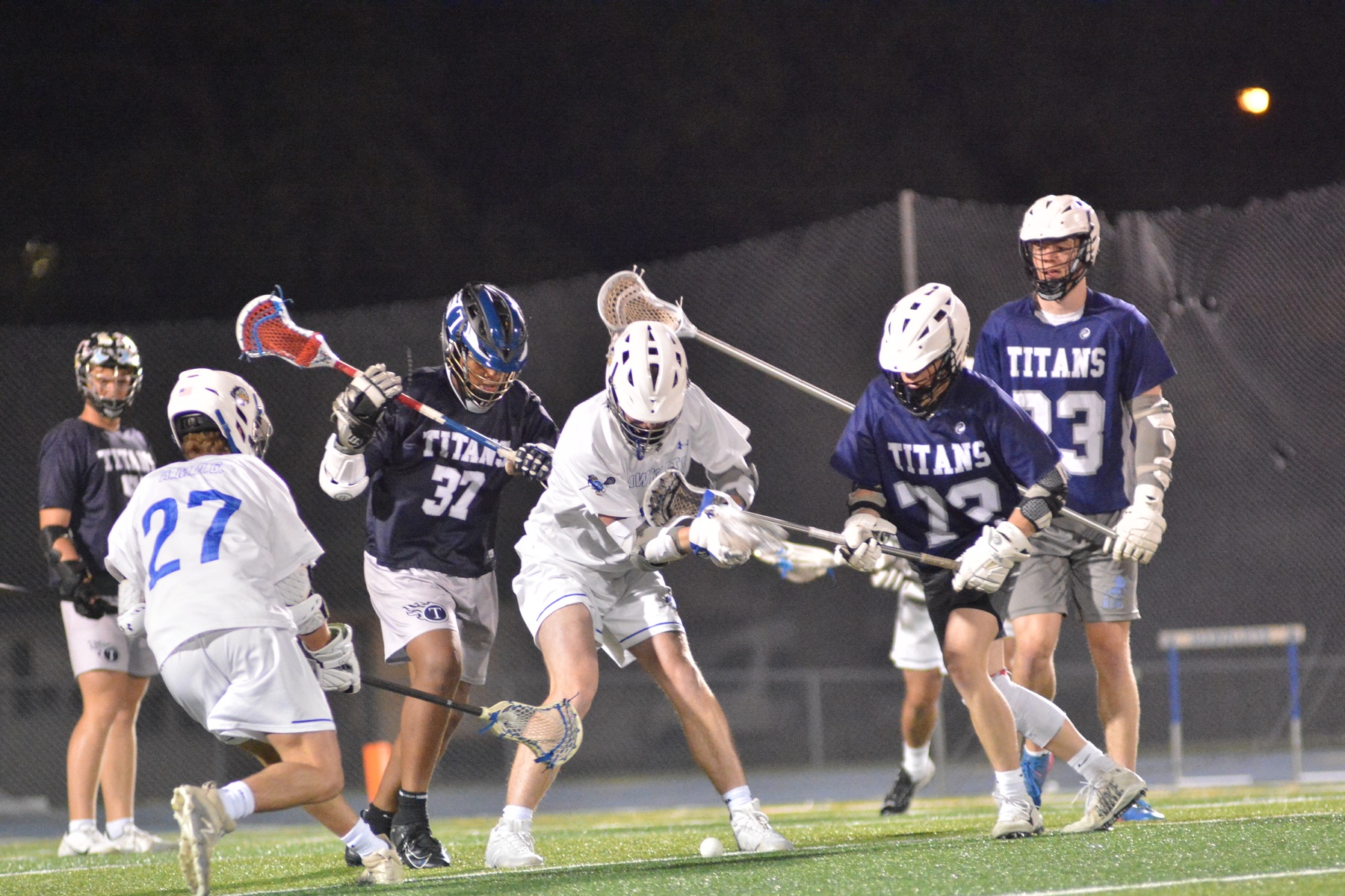 Lacrosse players battling for a ground ball at night